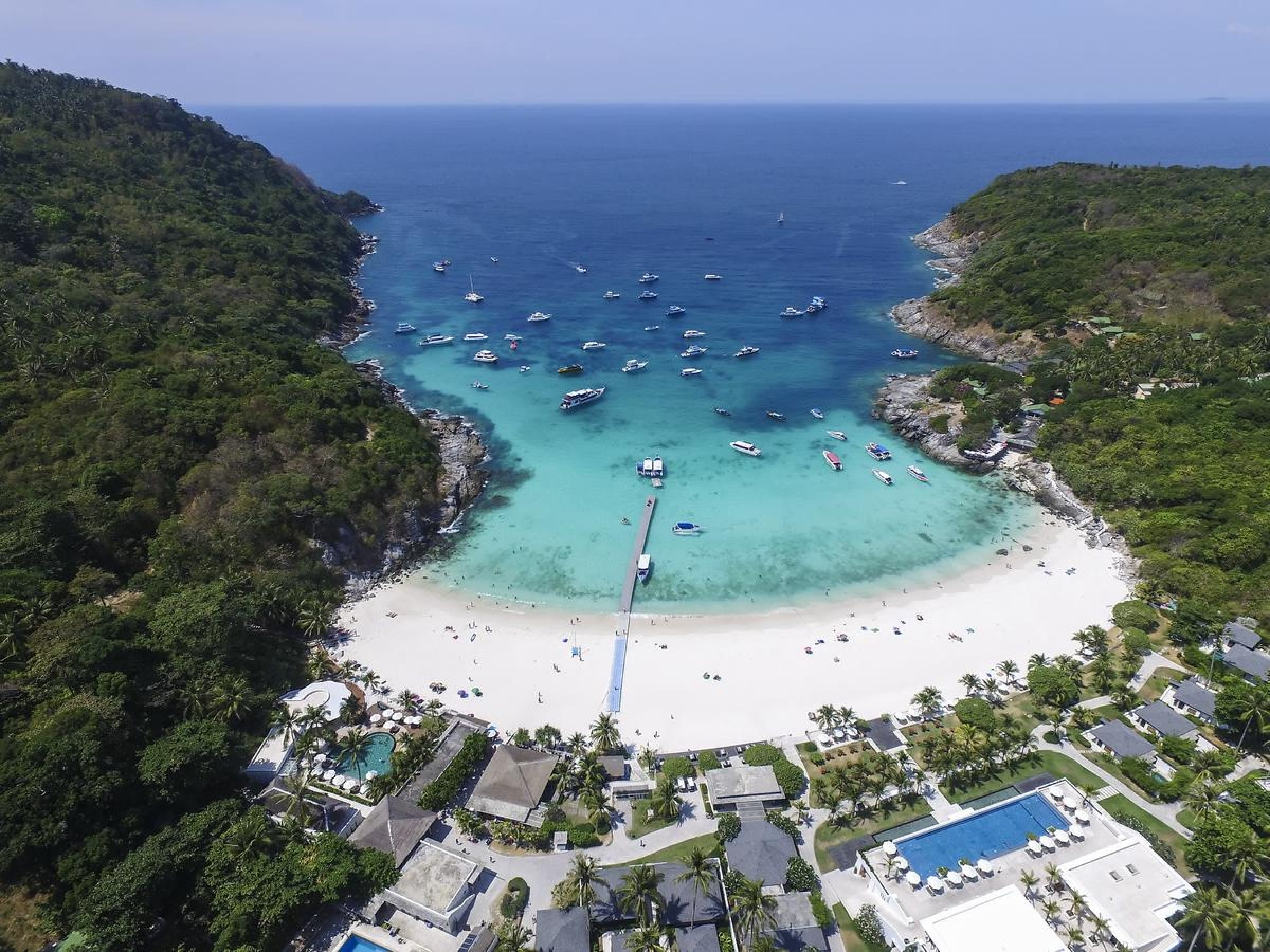 Caption: an aerial view of a beach with boats in the water